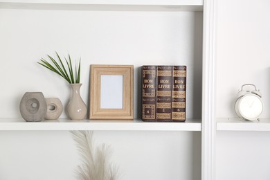 Photo of Different decor elements on white shelf in room. Interior design