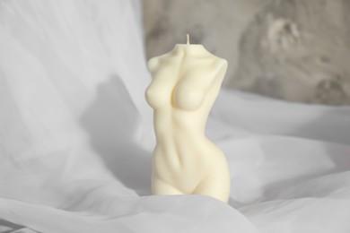 Photo of Beautiful female body shape candle on fabric