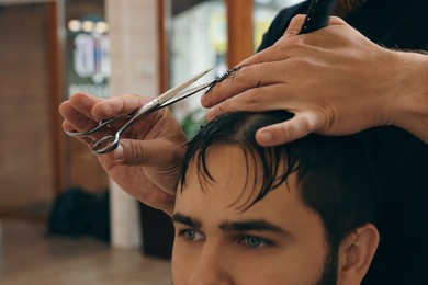 Photo of Professional hairdresser working with client in barbershop, closeup