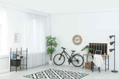 Photo of New bicycle near wall in stylish room interior