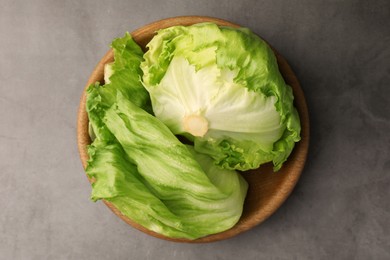 Bowl with fresh green iceberg lettuce head and leaves on grey table, top view