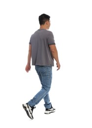 Man in casual outfit walking on white background, back view