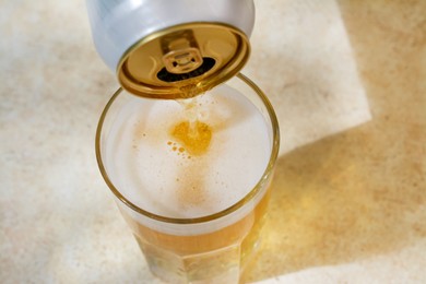 Photo of Pouring beer from can into glass on table, above view