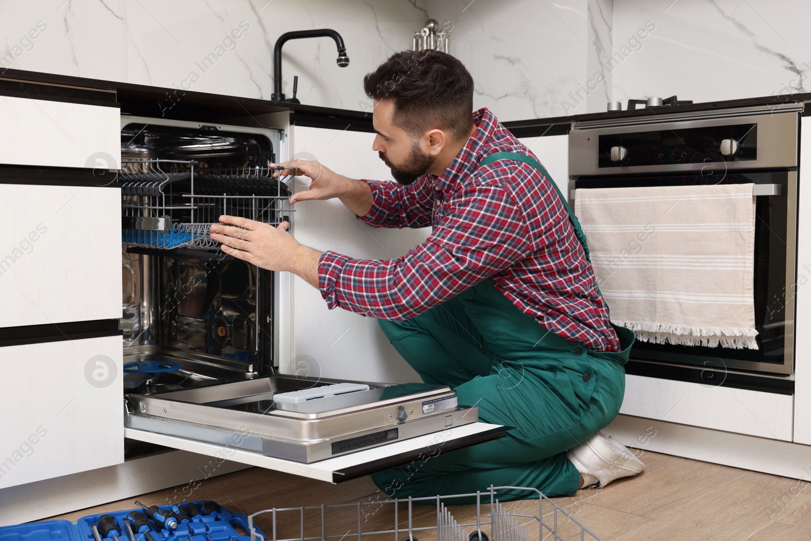 Photo of Serviceman repairing dishwasher cutlery rack in kitchen