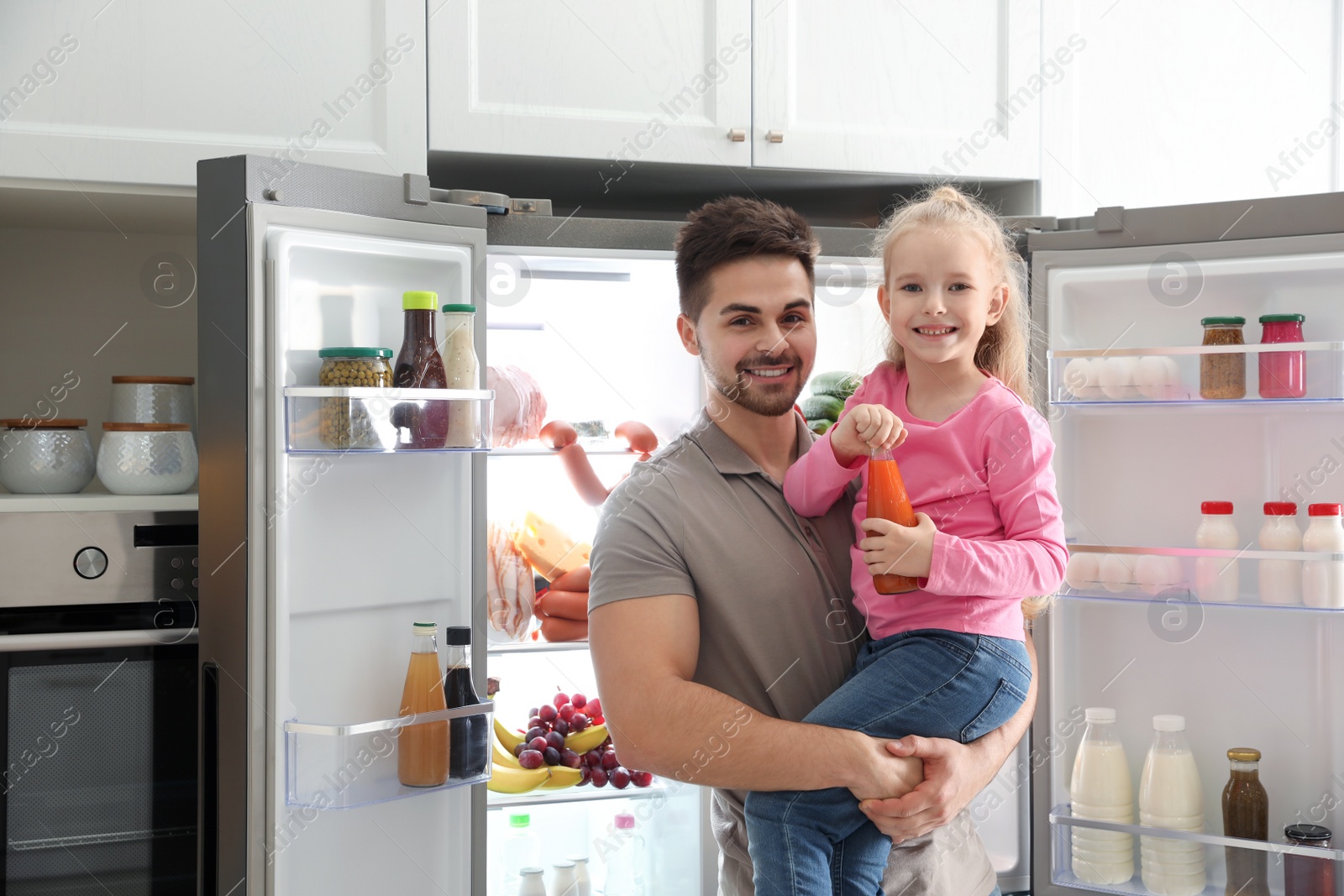 Photo of Young father with daughter near open refrigerator in kitchen