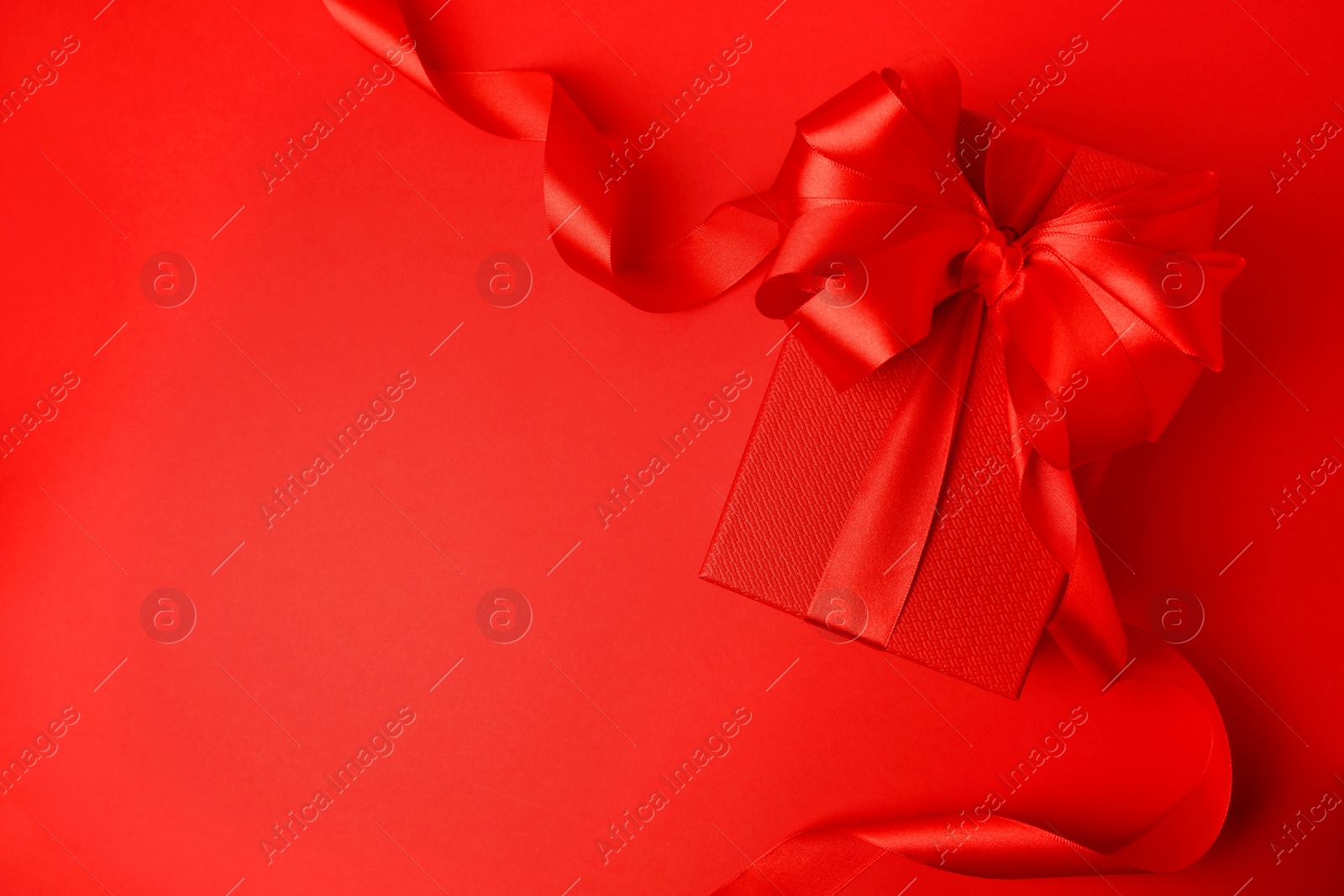 Photo of Beautiful gift box with bow on red background, top view. Space for text