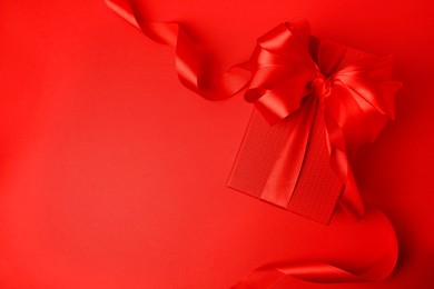 Beautiful gift box with bow on red background, top view. Space for text