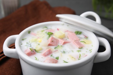 Photo of Delicious cold summer soup (okroshka) with boiled sausage on table, closeup