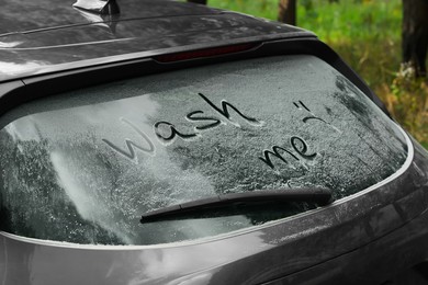 Phrase Wash me written on dirty car window outdoors, closeup