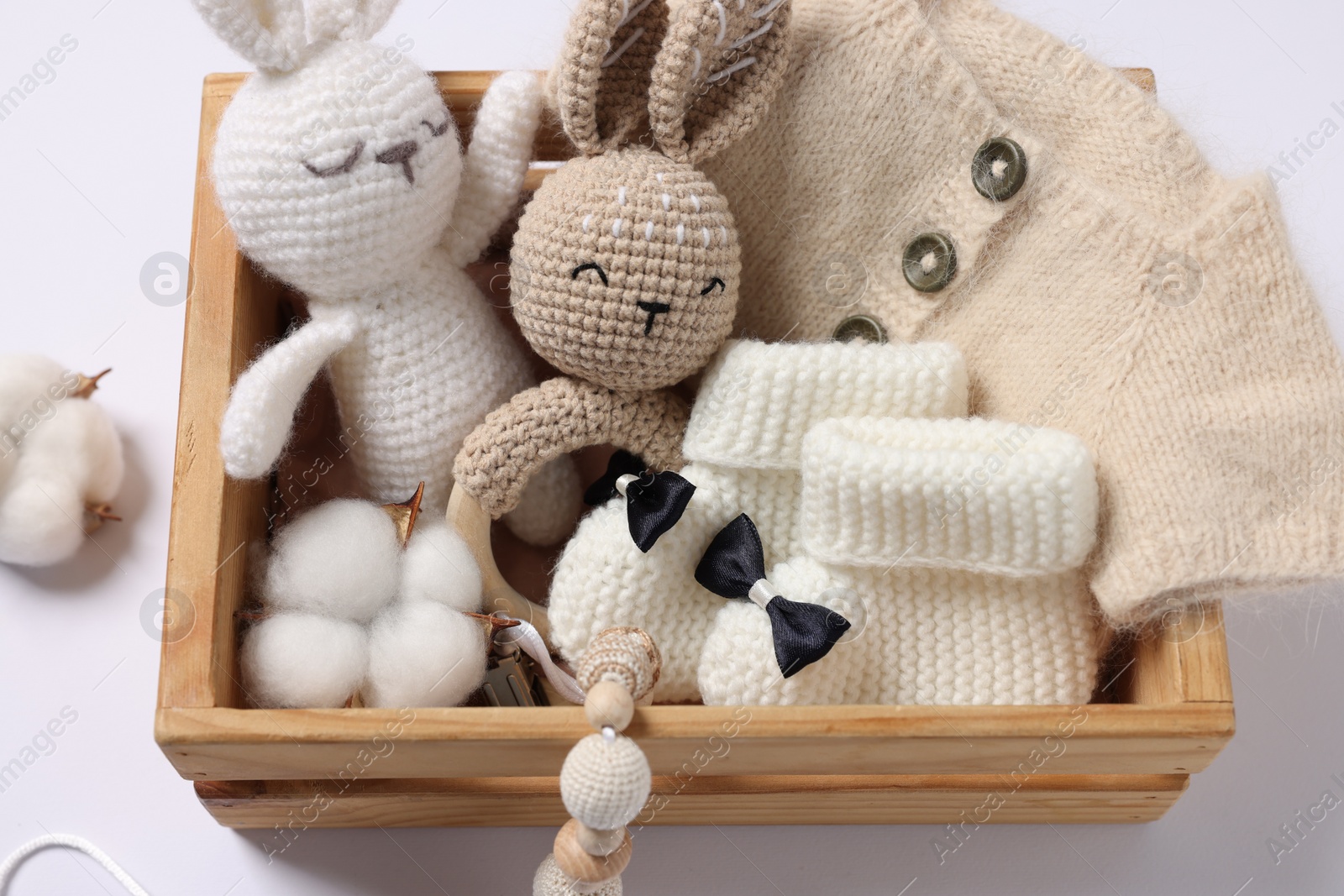 Photo of Different baby accessories and clothes in wooden crate on white background