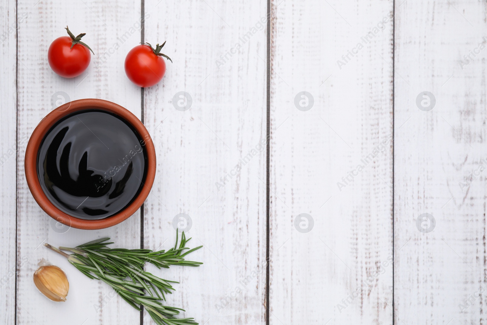 Photo of Organic balsamic vinegar and cooking ingredients on white wooden table, flat lay. Space for text