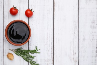 Photo of Organic balsamic vinegar and cooking ingredients on white wooden table, flat lay. Space for text