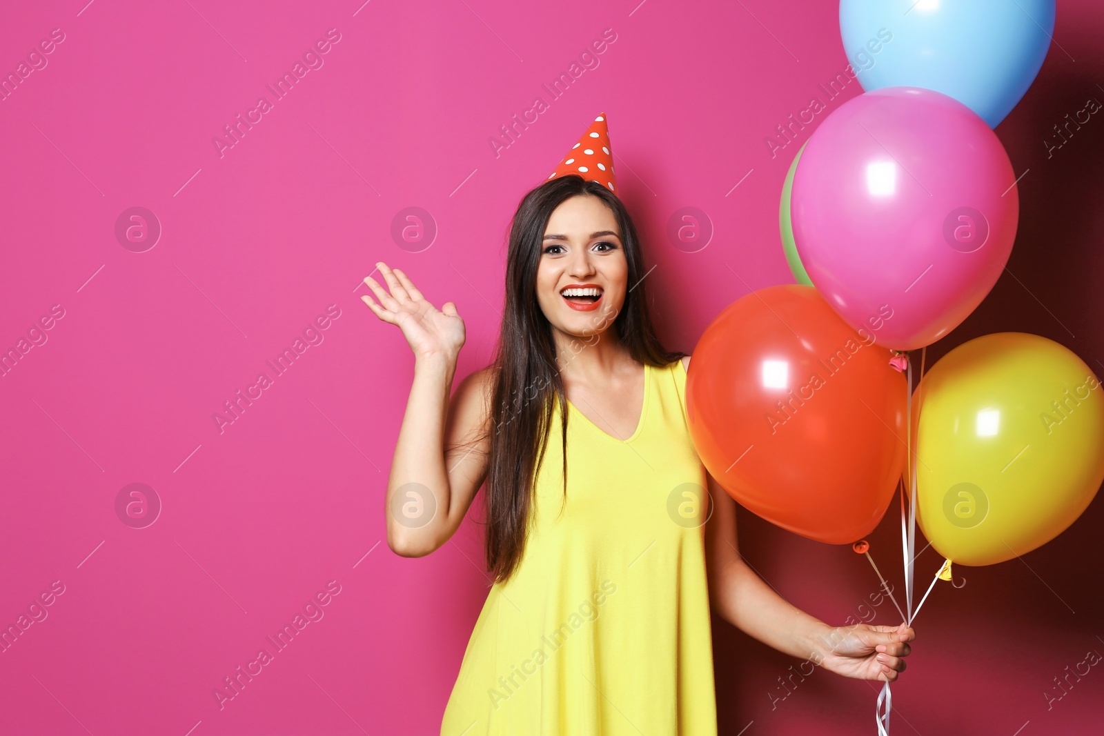 Photo of Young woman with bright balloons on color background. Birthday celebration