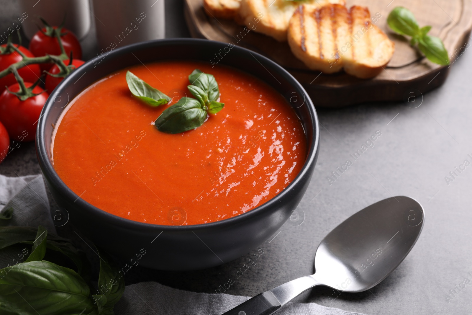 Photo of Delicious tomato cream soup in bowl on grey table, closeup