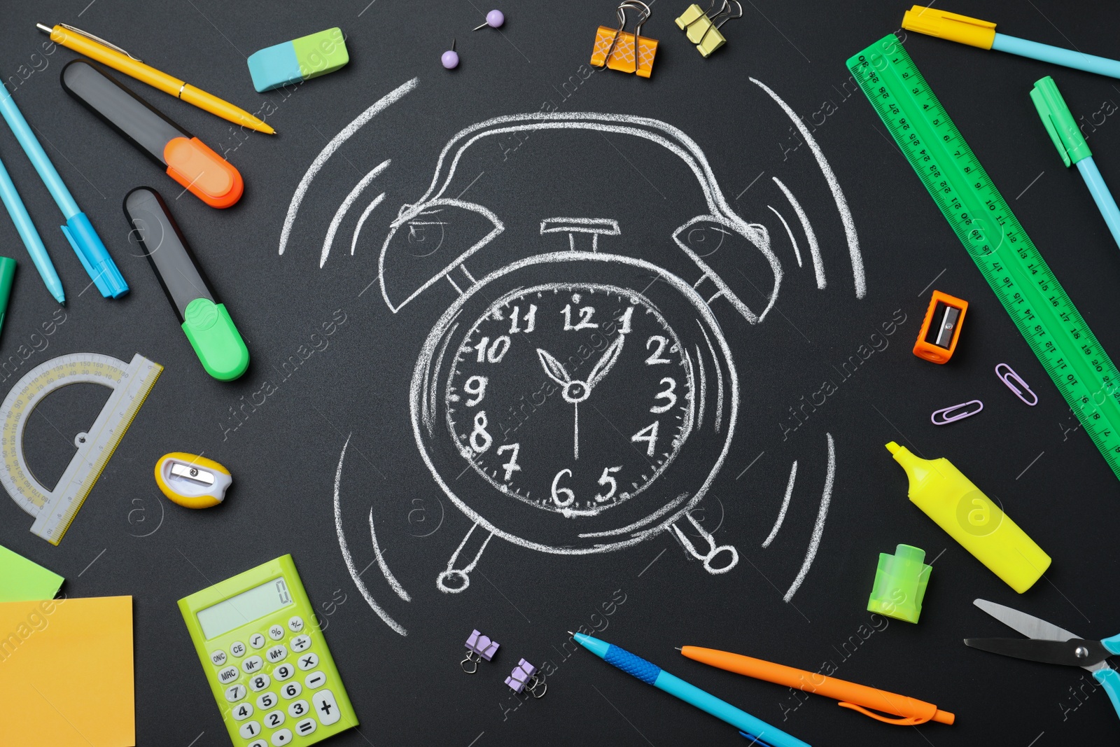 Photo of Flat lay composition with different stationery and drawn alarm clock on blackboard. School time