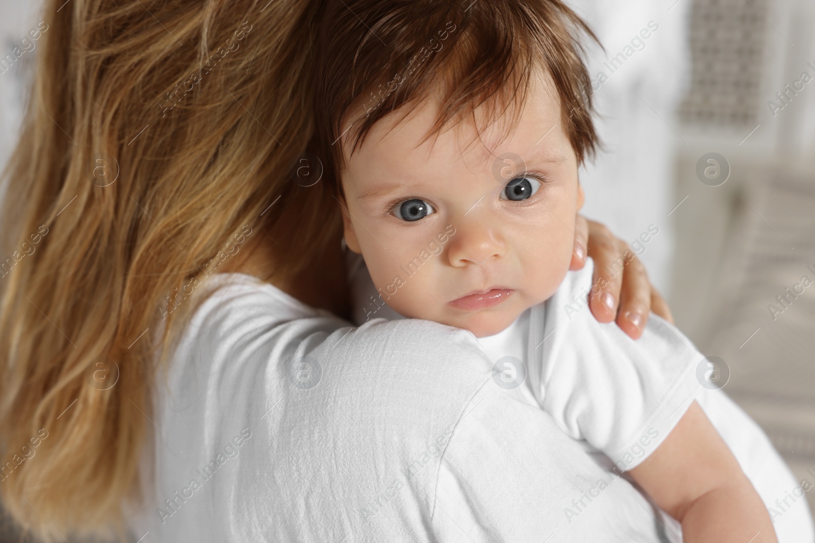 Photo of Mother hugging her cute little baby indoors, closeup