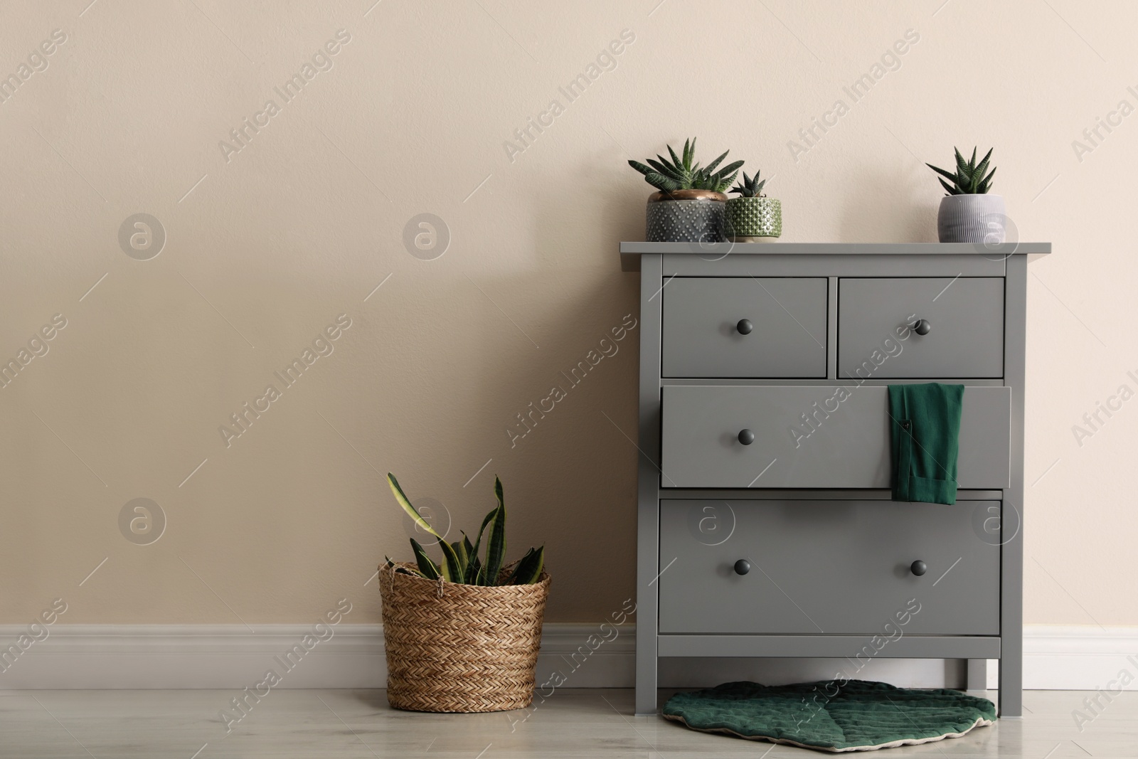 Photo of Room interior with grey chest of drawers near beige wall