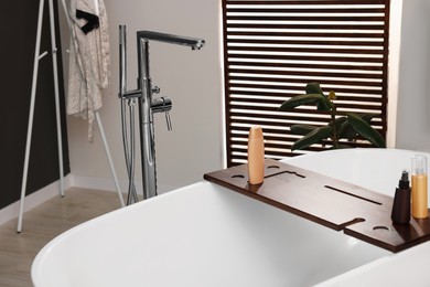 Photo of Stylish bathroom interior with ceramic tub and cosmetic products