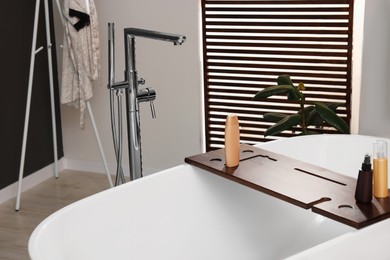 Stylish bathroom interior with ceramic tub and cosmetic products