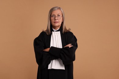 Photo of Beautiful senior judge with crossed arms on light brown background
