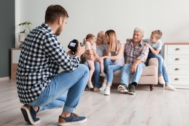 Photo of Professional photographer taking photo of family on sofa in studio