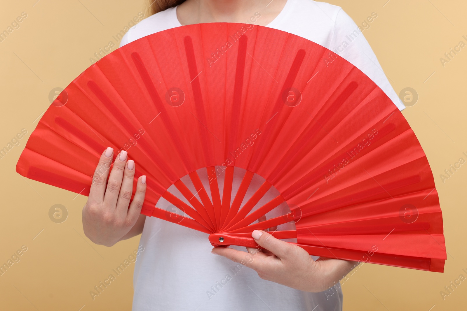 Photo of Woman with red hand fan on beige background, closeup