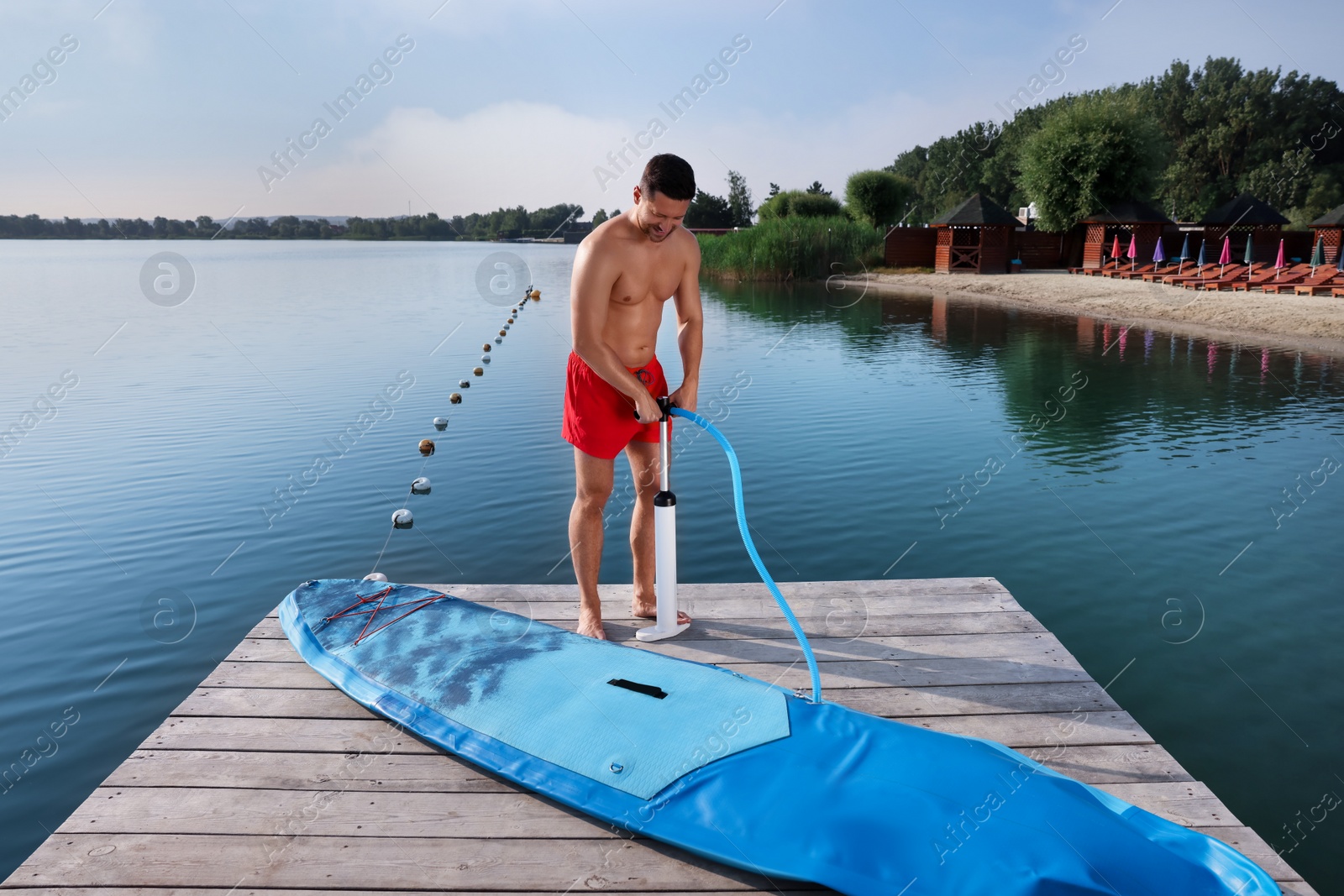 Photo of Man pumping up SUP board on pier