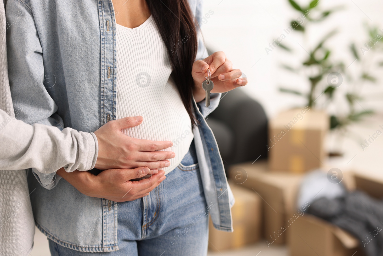 Photo of Pregnant woman and her husband with key in their new apartment, closeup. Space for text