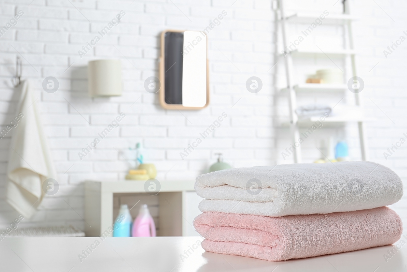 Photo of Stack of fresh towels on table in bathroom. Space for text