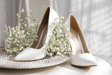 Beautiful wedding shoes, engagement ring and flowers on table indoors, closeup
