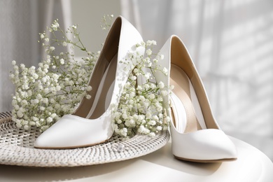 Photo of Beautiful wedding shoes, engagement ring and flowers on table indoors, closeup