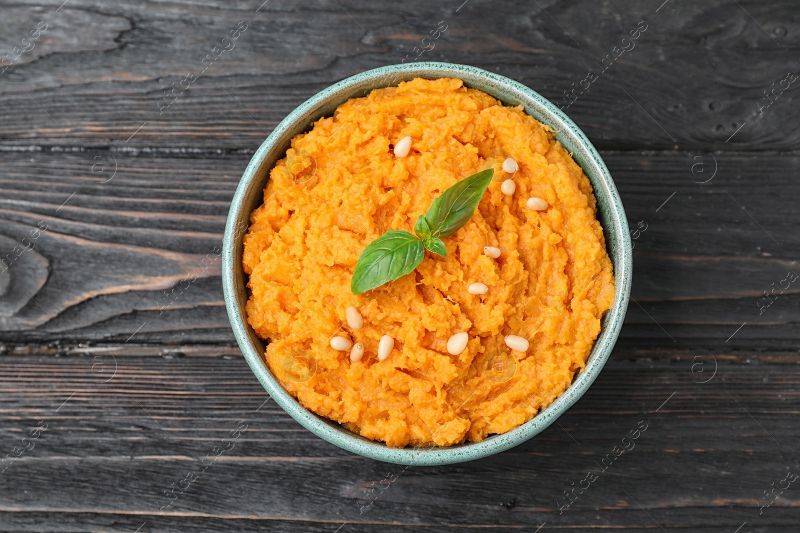 Photo of Bowl with mashed sweet potatoes on wooden table, top view