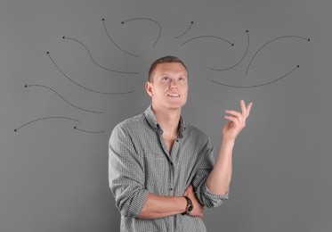 Image of Choice in profession or other areas of life, concept. Making decision, thoughtful young man surrounded by drawn arrows on color background