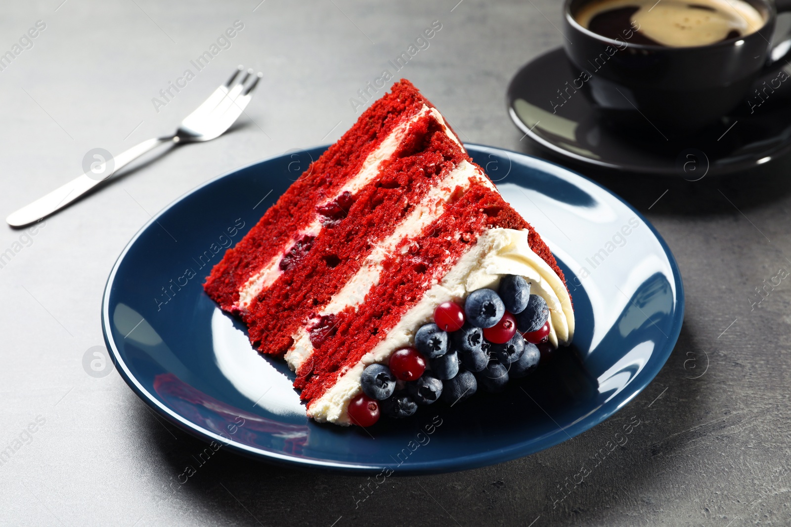 Photo of Plate with piece of delicious homemade red velvet cake on table