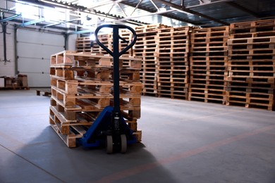 Modern manual forklift with wooden pallets in warehouse, space for text