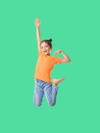Image of Happy cute girl jumping on dark aquamarine background