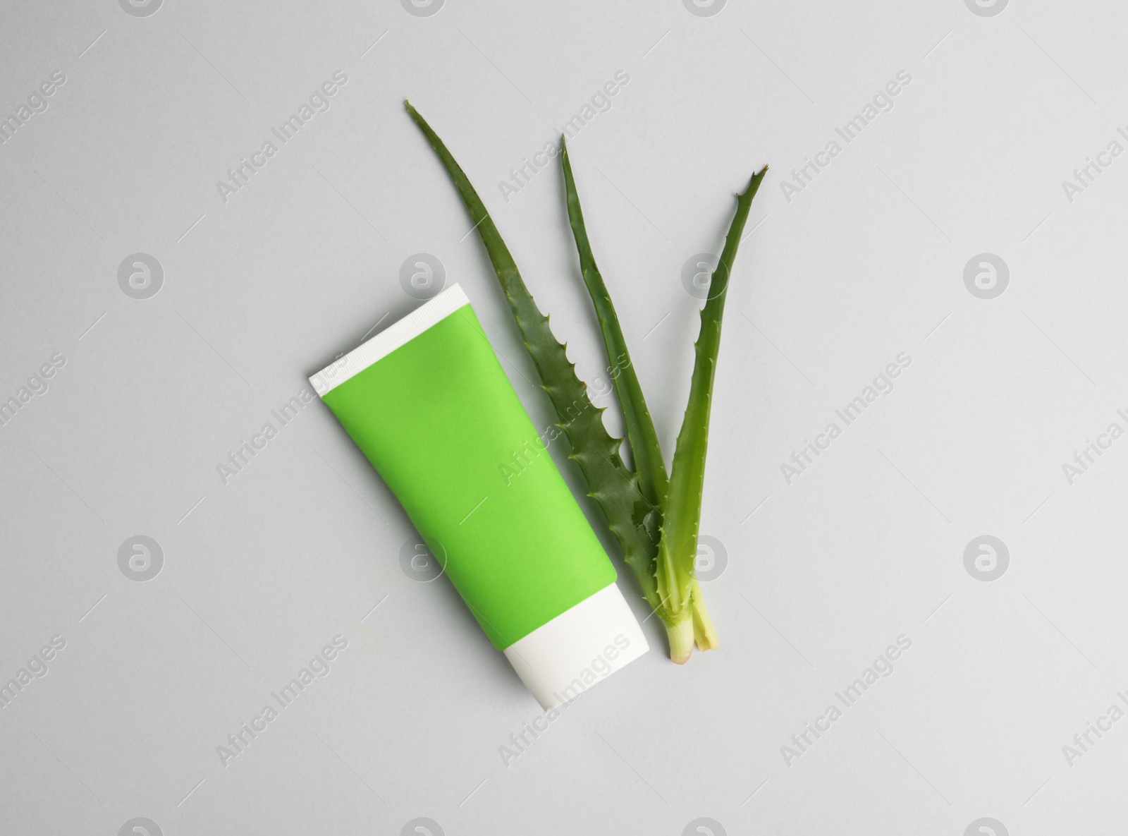 Photo of Tube of toothpaste and fresh aloe on light grey background, flat lay