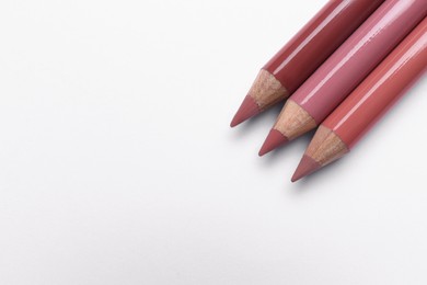 Photo of Different lip pencils on white background, top view. Cosmetic product