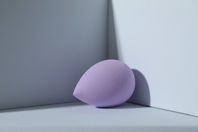 Photo of One violet makeup sponge on light background