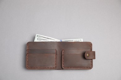 Photo of Stylish brown leather wallet with dollar banknotes on light grey background, top view. Space for text