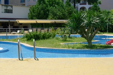 Photo of Terrace of hotel with swimming pool and tropical plants on sunny day