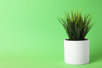 Photo of Beautiful artificial plant in flower pot on green background, space for text