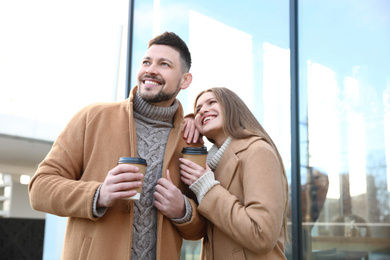 Photo of Lovely couple with cups of coffee on city street in morning