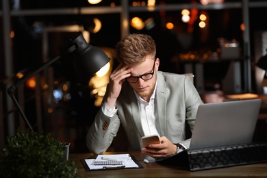 Photo of Young man working in office at night