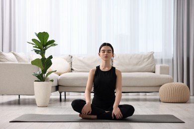 Photo of Beautiful girl meditating on yoga mat at home