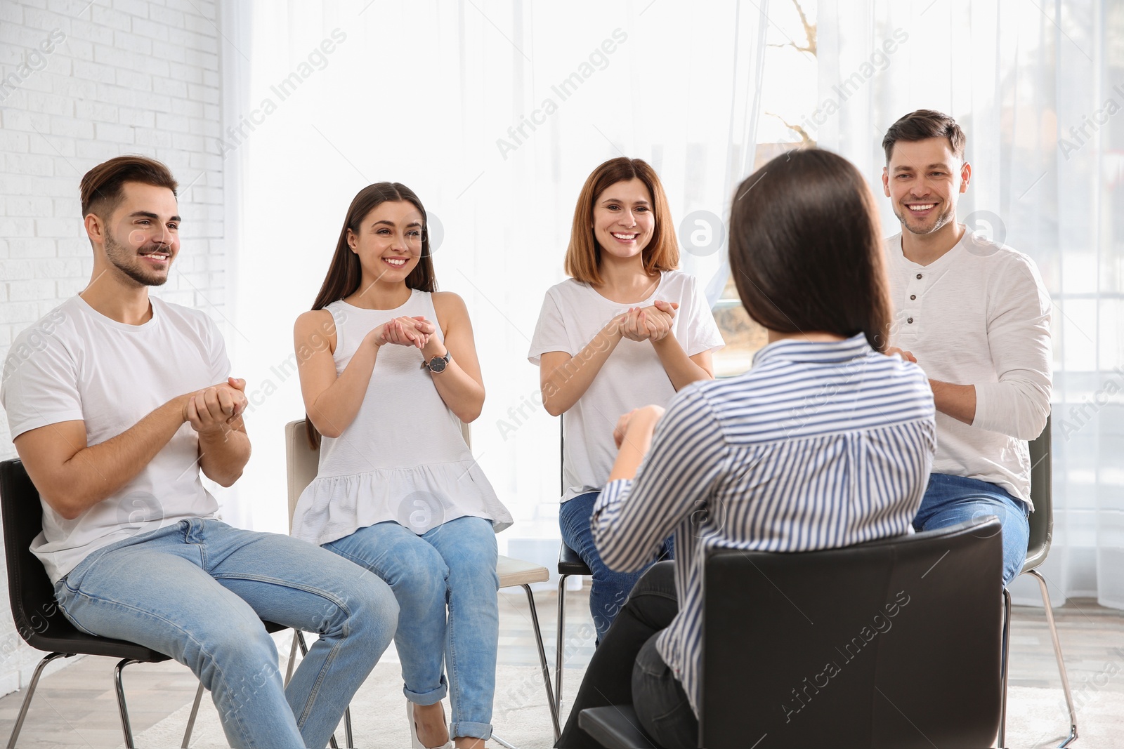 Photo of Group of young people learning sign language with teacher indoors