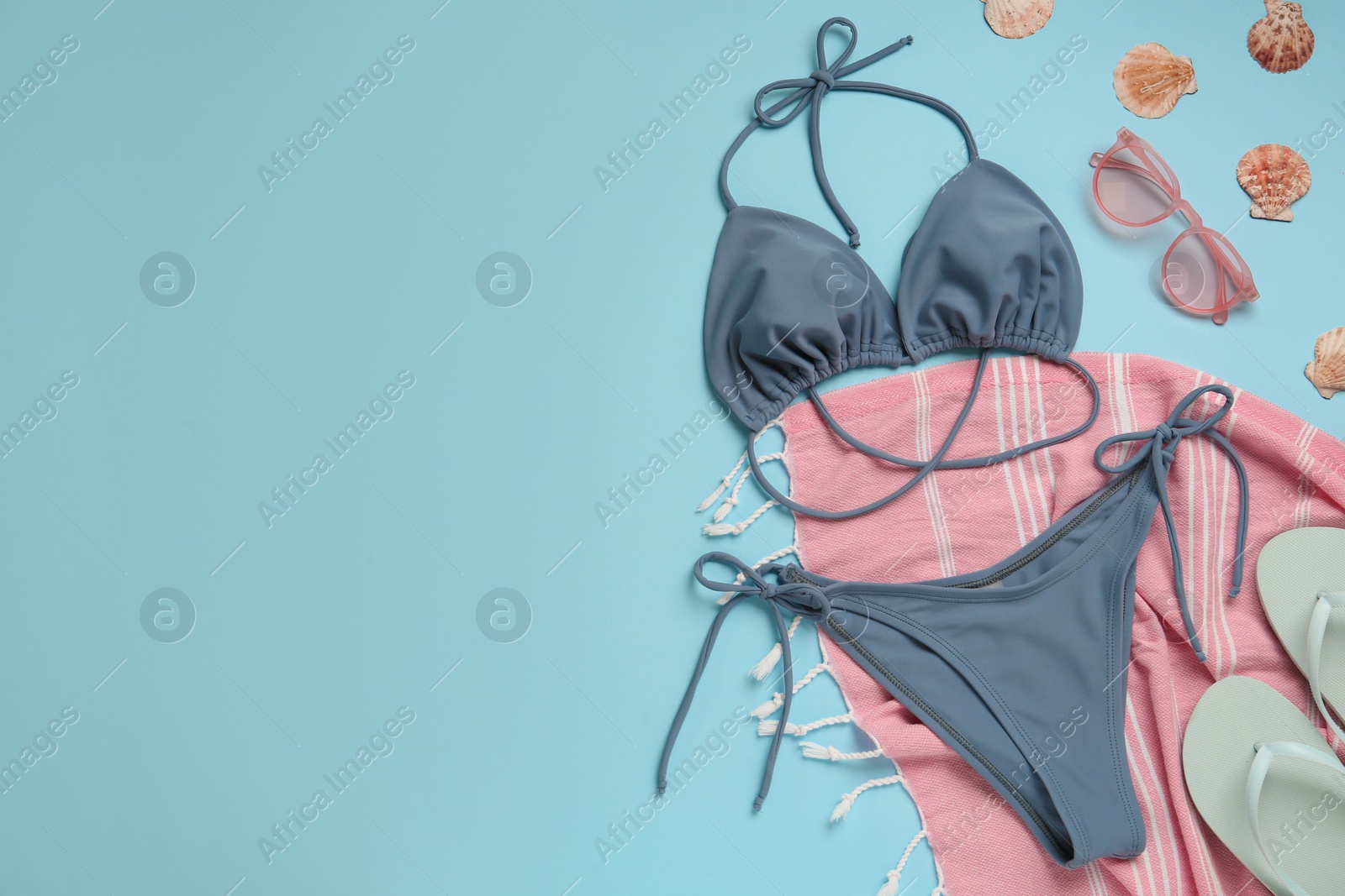 Photo of Stylish bikini and beach accessories on light blue background, flat lay. Space for text