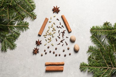 Christmas tree made of different spices and fir branches on light gray textured table, flat lay