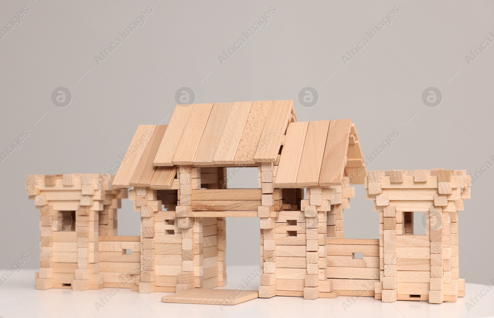 Photo of Wooden entry gate and box on white table against light grey background. Children's toy