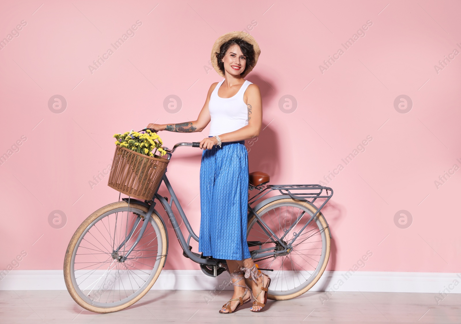 Photo of Portrait of beautiful young woman with bicycle near color wall